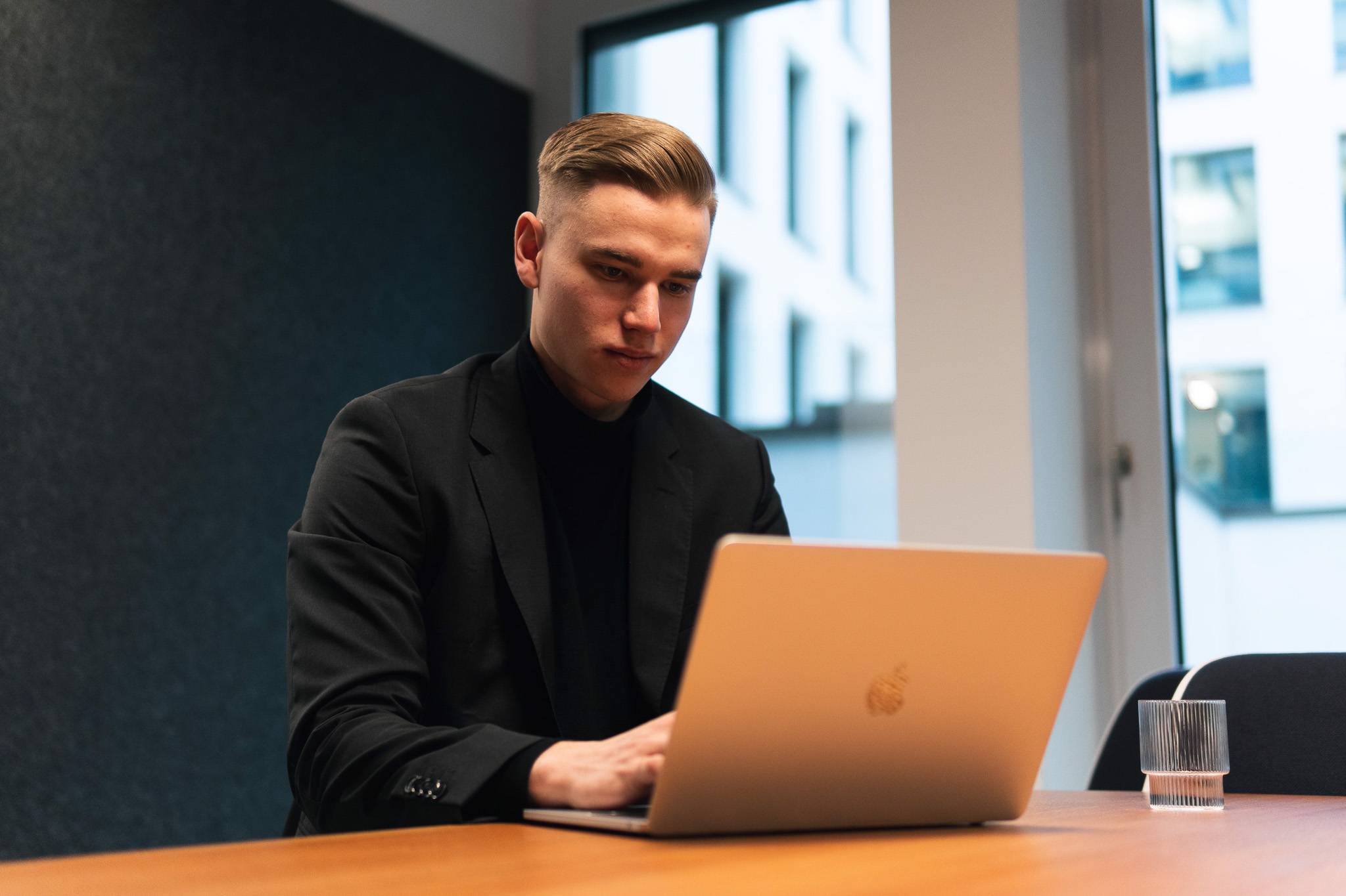 Nicholas Bode sitzt in einem Büro an seinem MacBook und arbeitet dabei das Branding eines neuen Kunden aus.
